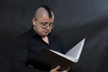 Bir çalışma klasörü okuma serseri. Siyah gömlek. Iroquois. Gözlük. Özenli ve ciddi görme.