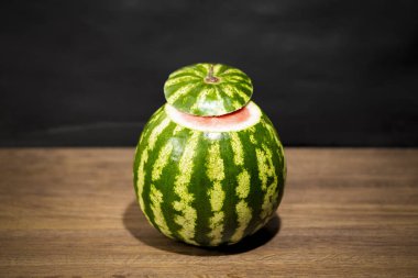 Karpuz ahşap bir masa üzerinde. Meyve üst kısmı kesilir. Bir olgun hamuru görebilirsiniz.