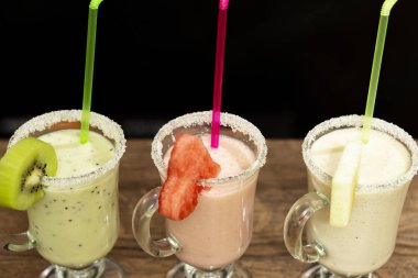 Güler yüzlü natürmort ahşap bir masa üzerinde. Gözlük kenarları kivi, karpuz ve ananas dilimleri vardır. Yukarıdan görüntülemek.