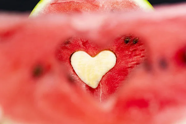 The shape of a heart on the background of a watermelon cut. The background is blurred. Paper heart on the cut.