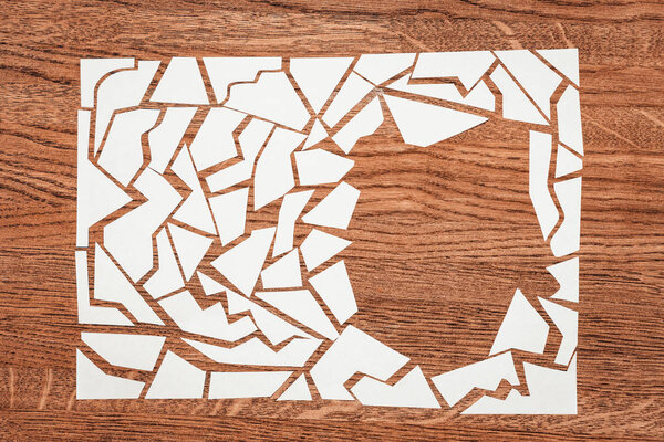 Rectangle laid out of cut pieces of white paper. The background of the tree is brown with a reddish tinge.