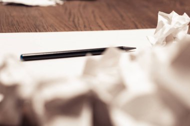 Beyaz sac ve kalem. Kağıt bir kahverengi ahşap zemin üzerinde yırtık ve buruşuk artıkları.