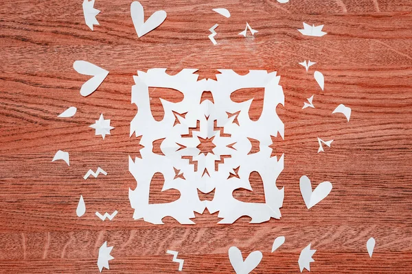 Closeup of New Year snowflakes cut from white paper on a wooden table. — Stock Photo, Image