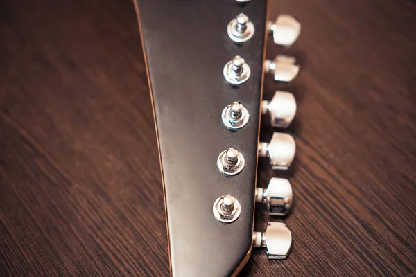 Pinzas de guitarra en la cabeza del cuello de una guitarra eléctrica. Sobre el fondo de una mesa de madera . —  Fotos de Stock