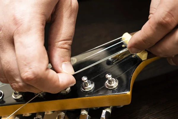 Installation strings of electric guitar pegs on the head of the neck of an electric guitar.