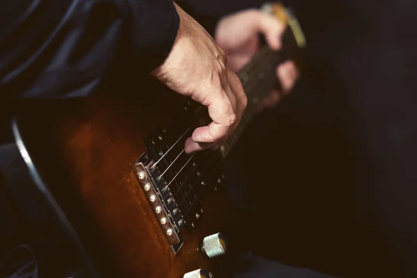 Les doigts rapprochés du musicien touchent les cordes d'une guitare électrique à six cordes . — Photo