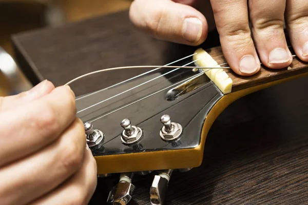 Installation strings of electric guitar through upper threshold on the head of the neck of an electric guitar.