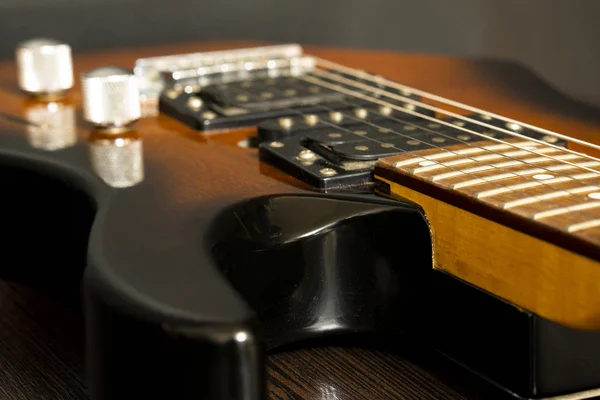 Guitarra eléctrica con seis cuerdas. Mesa de madera. Vista lateral . —  Fotos de Stock