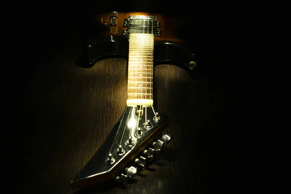 Guitarra eléctrica en una mesa de madera. Fondo oscuro . —  Fotos de Stock