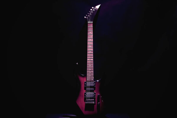 Red electric guitar on a black background. Located vertically.