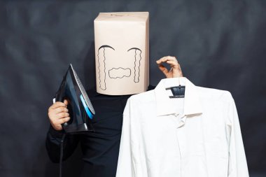 Duygu kavramı. Bir adam bir demir bir askı üzerinde asılı bir gömlek yanında tutar. Yüzünde bir ifade üzüntü ve yazık.