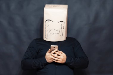 Duygular kavramı. Bir adam, bir cep telefonu için bir ileti görünüyor. Üzüntü ve merhamet ifadesi bir yüzünde. Gözyaşları haddelenmiş. Arka plan gri bulanık.