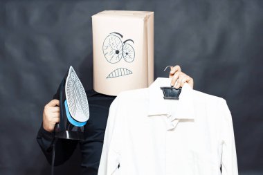 Duygu kavramı. Bir adam bir demir bir askı üzerinde asılı bir gömlek yanında tutar. Yüzünde bir ifade öfke ve kararlılık.