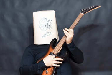 Duygu kavramı. Adam gitar çalıyor. Yüzünde bir hoşnutsuzluk ve öfke ifadesi.