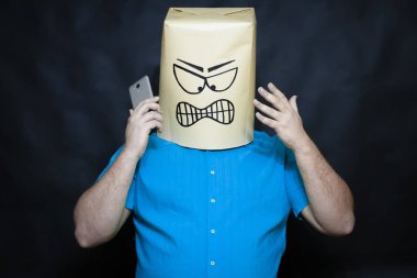 Duygular kavramı. Bir adamın yüzündeki ifadeye yoğun irritasyon ve sinirlilik anlamına gelir. Sağ elinde, o bir akıllı telefon tutar.