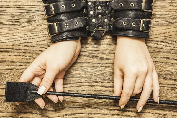 BDSM elleri kelepçeli. Ahşap arka plan üzerinde yapay penis