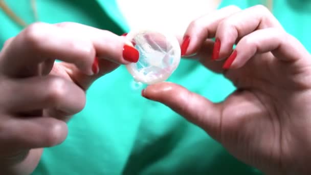 Понятие безопасного секса. распаковывая презерватив в руке женщины — стоковое видео