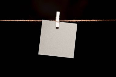 Siyah arka plan. Bir ip üzerinde asılı bir clothespin ile beyaz kağıdın.