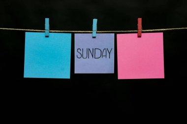 Uzay kopyalayın. Siyah arka plan üzerine üç çıkartmaları. Pazar. Gri, pembe ve gök adet ip clothespins bağlı kağıt.