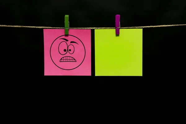 Ricevuto. Due adesivi. Lasciato sul foglio rosa di un volto sorridente con un'espressione di rabbia . — Foto Stock