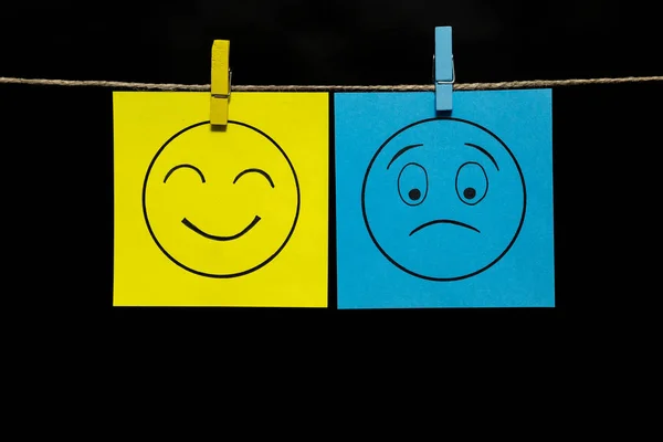 Copiar espacio. Dos pegatinas multicolores. En el amarillo de una cara sonriente de sonrisa, en el azul decepcionado . —  Fotos de Stock