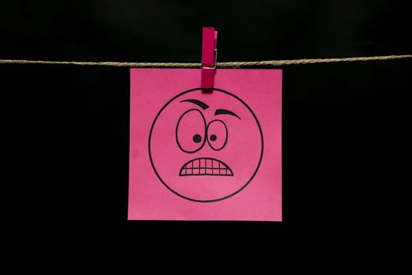 Espace de copie. Sticker rose. Expression faciale de colère. Le papier est attaché à la corde avec une pince à linge . — Photo