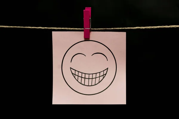 Copy space. White sticker. On face an expression of gaiety. The paper is attached to the rope with a clothespin. — Stock Photo, Image
