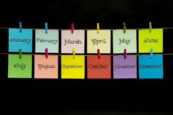 Copy space. Twelve multi-colored sheets with the names of the months of the year. Stickers are attached to the rope with clothespins. — Stock Photo, Image