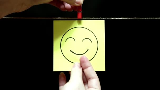 Emozioni. Sul volto del sorriso e layout amichevole.Il foglio è fissato manualmente con una molletta sulla corda . — Video Stock