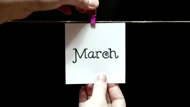 Mese dell'anno. Primavera. Sul foglio iscrizione marzo. Il foglio è fissato manualmente con una molletta sulla corda . — Video Stock