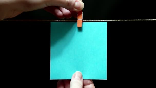 Copy space. Pure blue sticker. The sheet is manually attached with brown a clothespin on the rope. — Stock Video