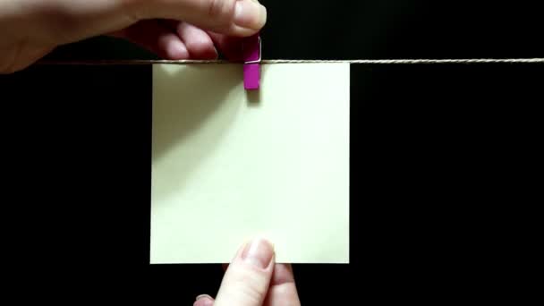Copy space. Pure white sticker. The sheet is manually attached with red a clothespin on the rope. — Stock Video