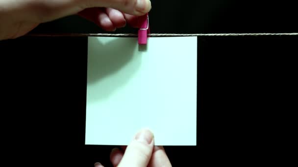 Copy space. Pure white sticker. The sheet is manually attached with a clothespin on the rope. — Stock Video