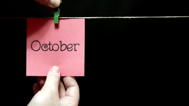 Two multicolored stickers. On left pink a sheet inscription October. On the right white a sheet an expression of festive mood. — Stock Video