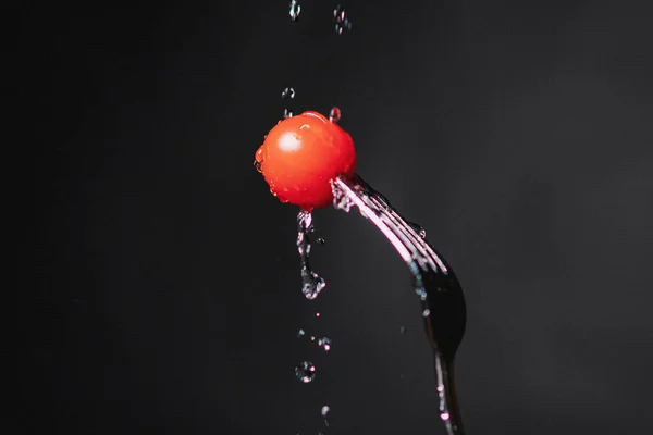 Tomato on a fork. Freeze motion splash water — Stock Photo, Image