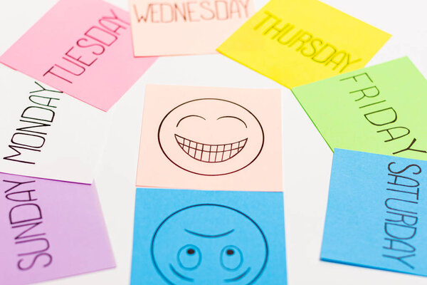 Листы бумаги разного цвета расположены в дуге. У них есть имя одного дня недели, написанного на них.