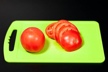 Sarı kesme tahtasındaki kırmızı taze domatesler. Koyu arkaplan.