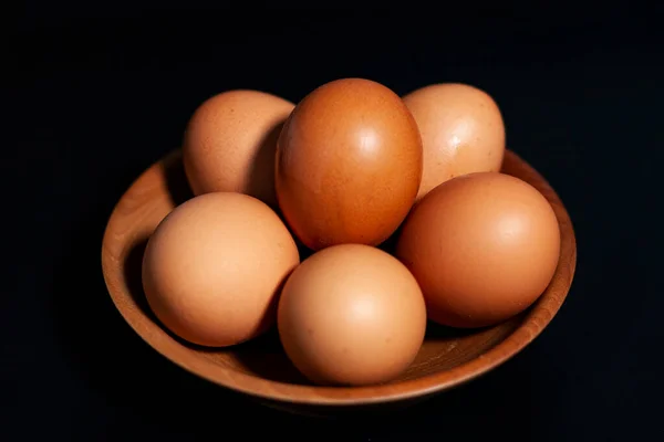 Ovos de galinha em uma xícara no canto inferior esquerdo do quadro. Em fundo escuro. — Fotografia de Stock