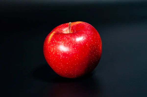 Maçã vermelha fresca sobre um fundo escuro. Cor natural brilhante da fruta. — Fotografia de Stock