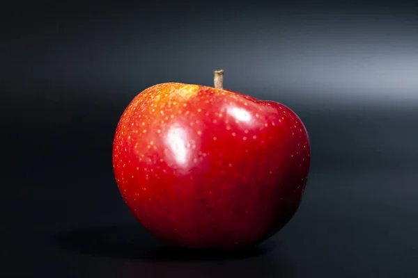Maçã vermelha fresca sobre um fundo escuro. Cor natural brilhante do feto de maçã suculento. — Fotografia de Stock