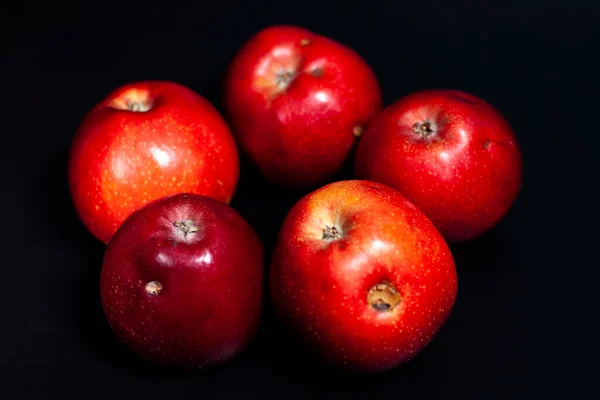 Five fresh red apples in the center of the screen. Some fruits have defects.