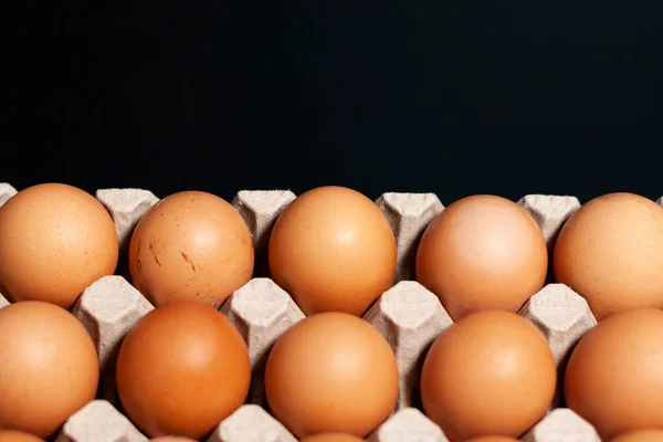 Bandeja de ovo com produto na parte inferior da tela em um fundo escuro. A parte superior é gratuita para publicidade. — Fotografia de Stock