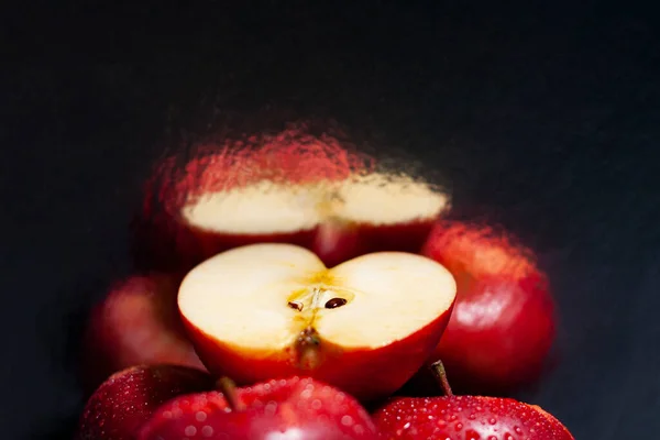 İki taze kırmızı elma ve yarım sulu meyve. Görüntüleri duvarın ayna yüzeyine yansıyor.. — Stok fotoğraf