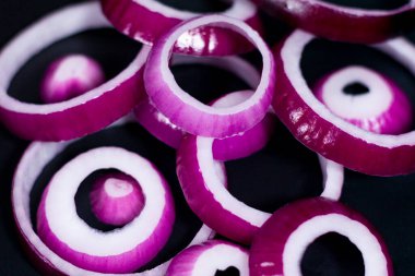 Koyu arkaplanda dilimlenmiş kırmızı soğan. Yığın biçiminde konum.