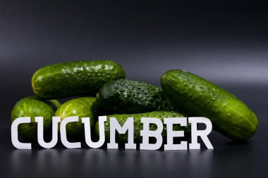 Çerçevenin ortasında taze yeşil salatalık yığını var. Üstteki kısım bedava. Karanlık arka plan..