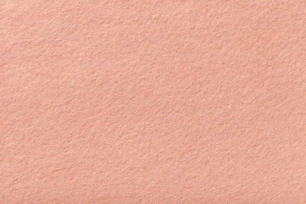 Light pink matte background of suede fabric, closeup. Velvet texture of seamless coral woolen felt.