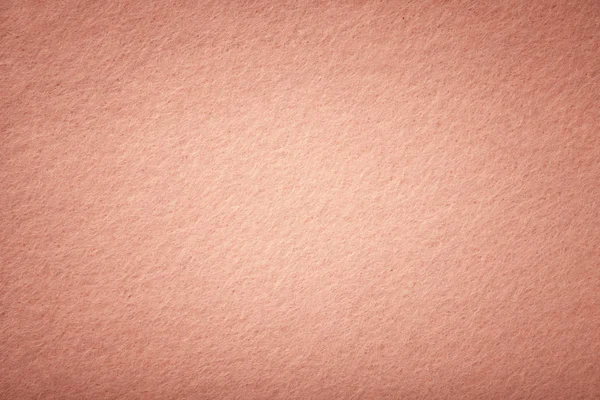 Rose gold matte background of suede fabric, closeup. Velvet texture of seamless coral woolen felt with vignette.