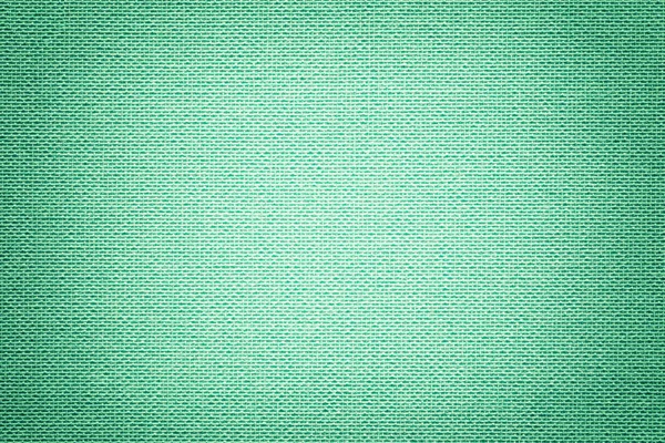 Light green background from a textile material with wicker pattern, closeup. Structure of the turquoise fabric with texture. Cloth cyan backdrop with vignette.