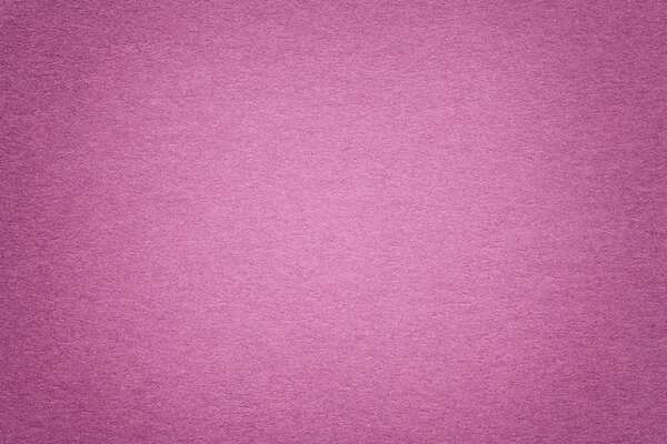 Texture of vintage dark purple paper background with vignette. Structure of dense magenta kraft cardboard with frame. Felt pink gradient backdrop closeup.