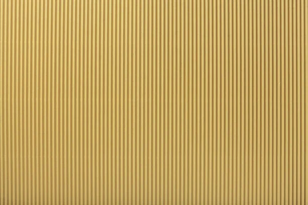 Texture of corrugated light golden paper, macro. Striped pattern of yellow cardboard background, closeup.